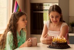 Close-up of girl blowing out candles on birthday cake.