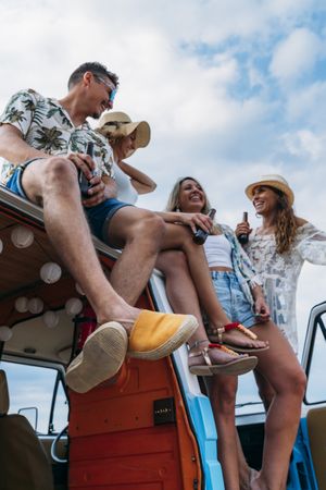 Relaxed friends comfortable placing on top of blue car
