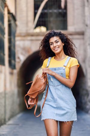 Content Arab woman walking through quiet street with arch
