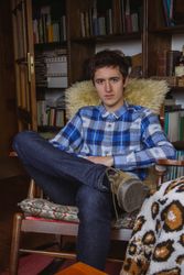Young man with plaid shirt and jeans sitting on rocking chair
