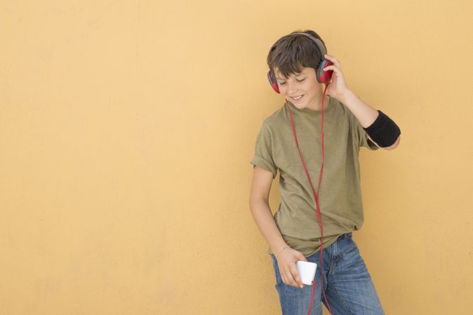 Happy teen wearing a green T-shirt listening to music on headphones