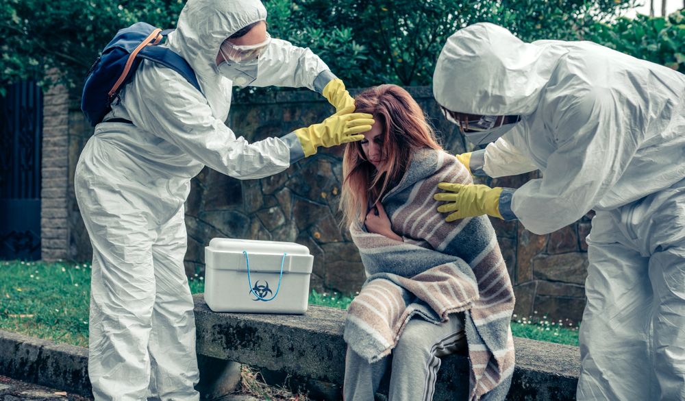 Doctors in protection suits caring for a woman