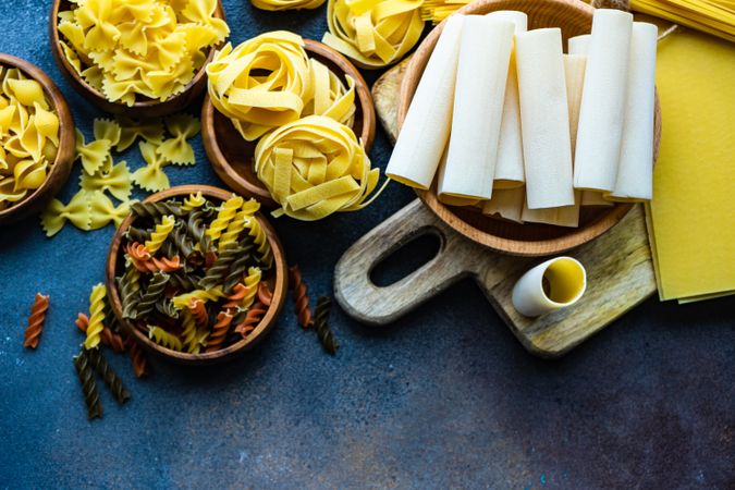 Top view of variety of bowls of dry Italian pasta with copy space