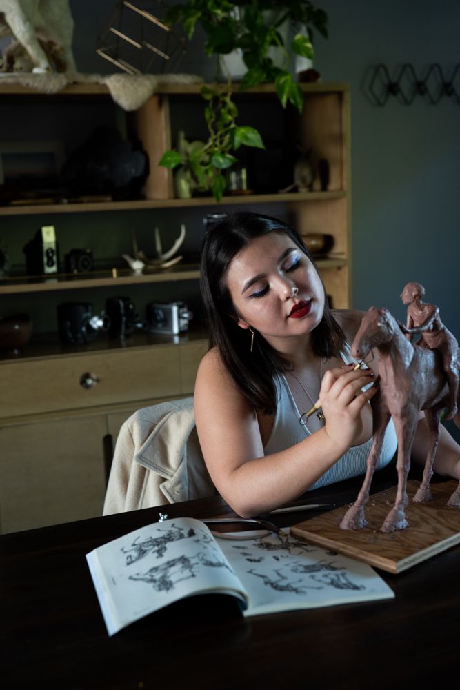 Young biracial woman sculpting clay horse