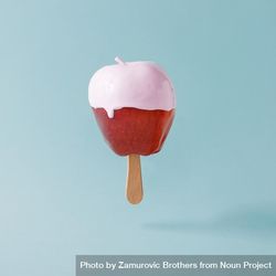 Apple on stick with pink syrup on pastel blue background 0Larr5