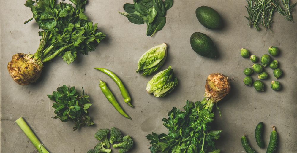 Arrangement of fresh green garden vegetables on concrete surface