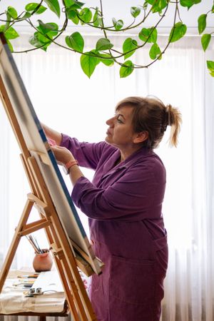 Adult woman painting canvas at home