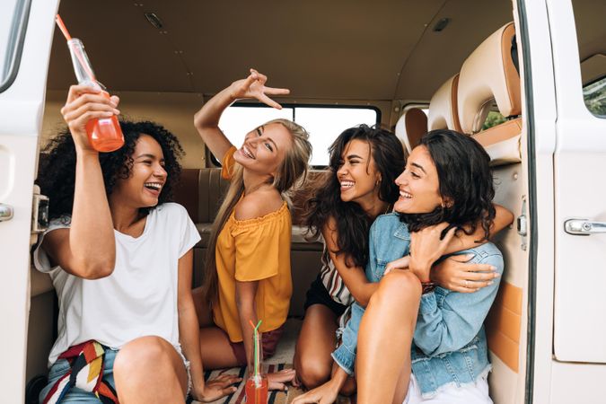 Female friends having drinks and and laughing in a van