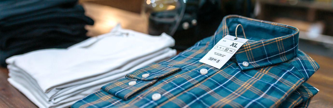 Close up of label with price and size over a blue plaid shirt on industrial style store