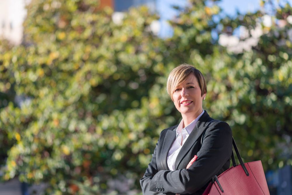 Proud businesswoman standing with arms crossed in front of hedge