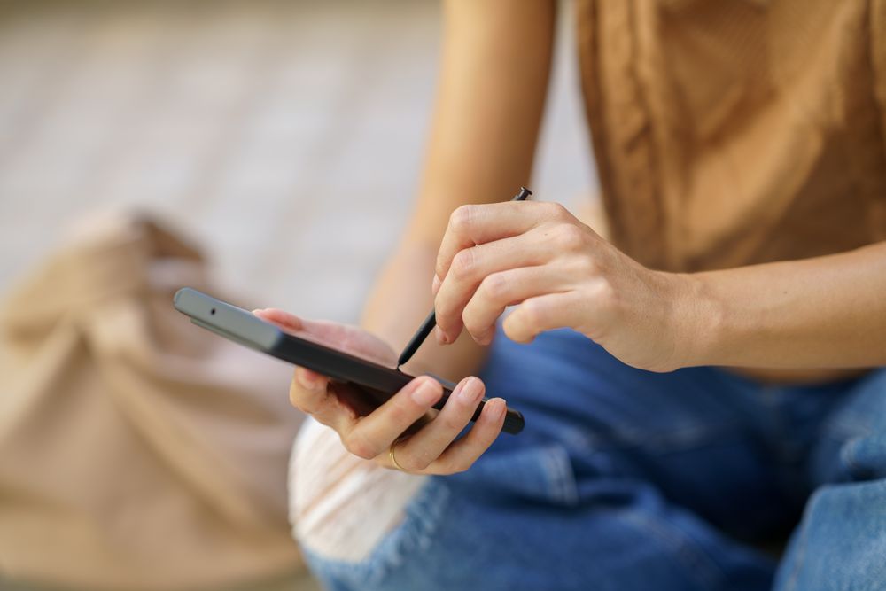 Close up of woman using stylus on smartphone
