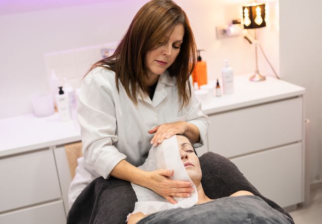 Beautician steaming face of female customer in beauty salon