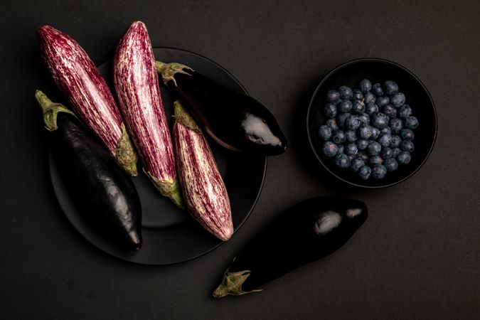 Ripe eggplants and blueberries on dark tabletop
