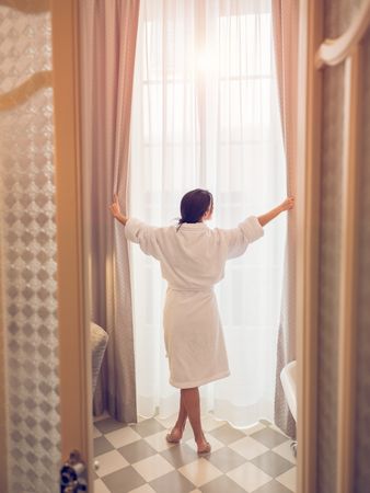 Unrecognizable female near window in hotel bathroom
