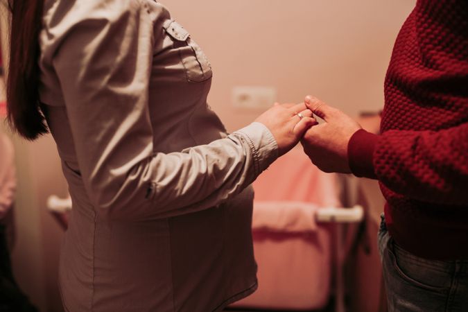 Expecting couple holding hands in baby room
