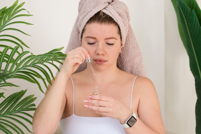 Woman applying skincare serum indoors.