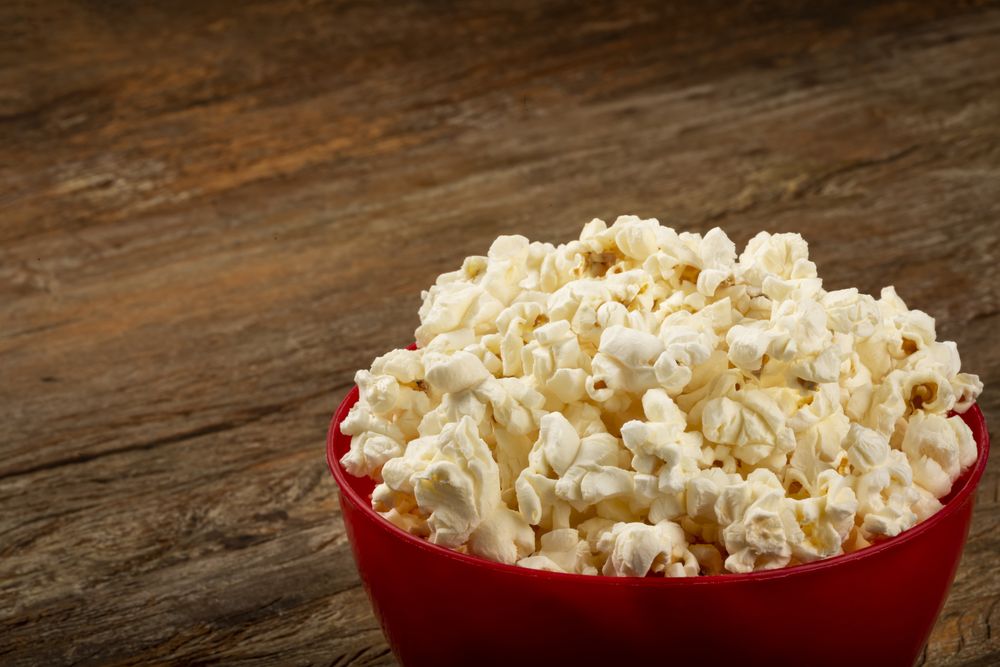 Bowl with salted popcorn sore the table.