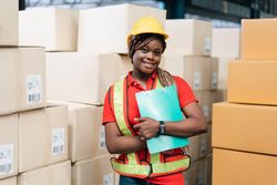 Woman in PPE gear standing with clipboard in front of store boxes