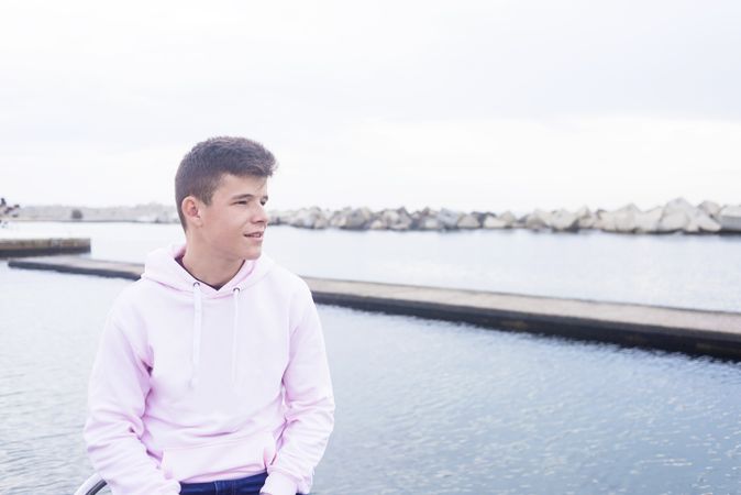 Young male teenager standing on rock breakwater with copy space