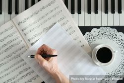 Person writing musical notes on piano 0WAvM4