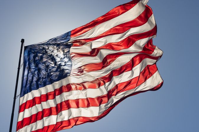 Backlit American Flag Waving In Wind Against a Deep Blue Sky