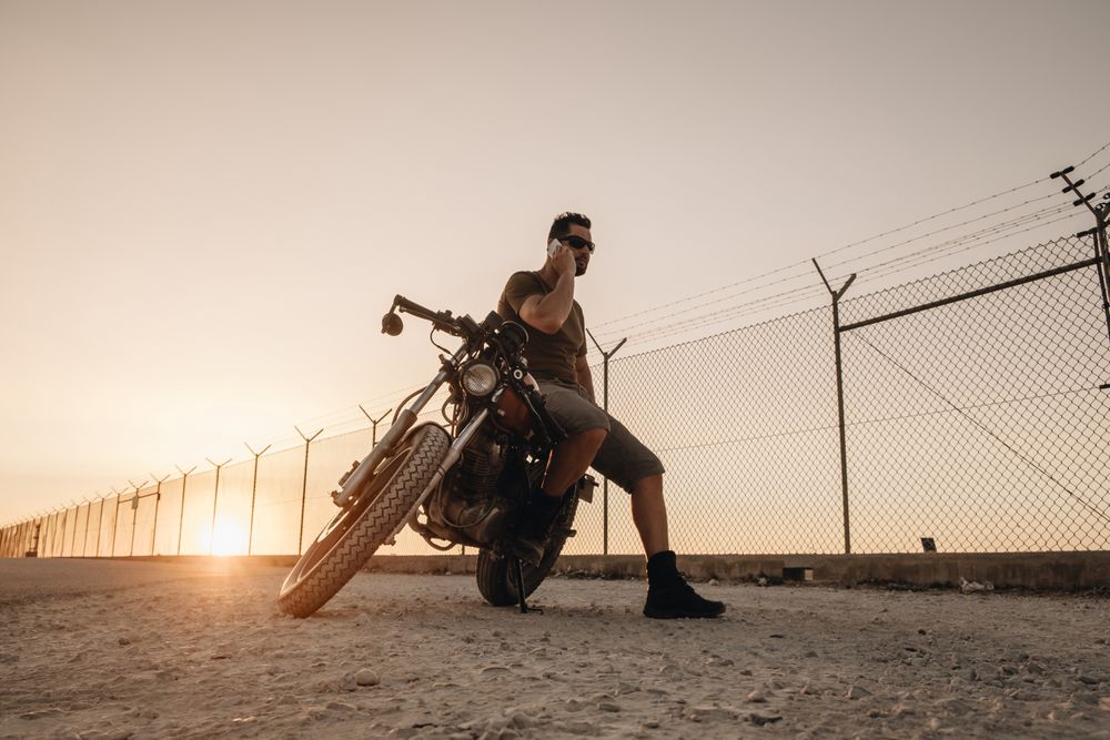 Man sitting on motorcycle and surfing mobile