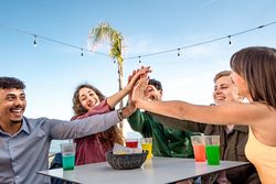 Diverse group of friends high-fiving at outdoor cafe by the sea