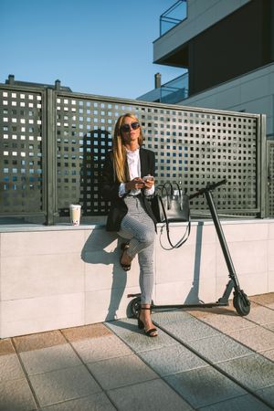 Businesswoman using mobile with her scooter next
