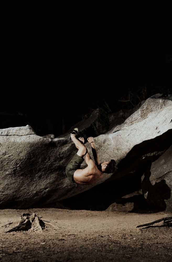Man practicing rock climbing among large rocks in a forest
