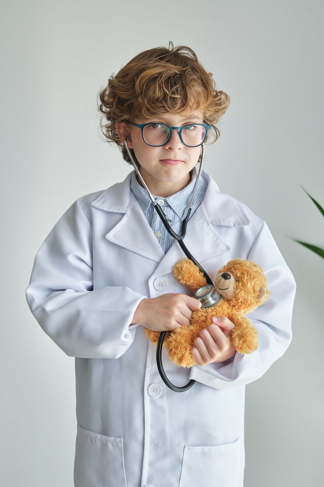 Boy doctor with stethoscope and toy bear during checkup