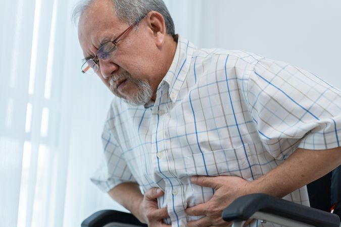 Older male with his hand holding his stomach in pain
