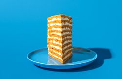 Sliced of honey layered cake, in bright light isolated on a blue background