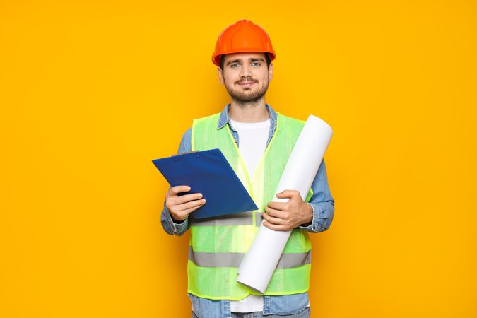 Young man civil engineer on yellow background
