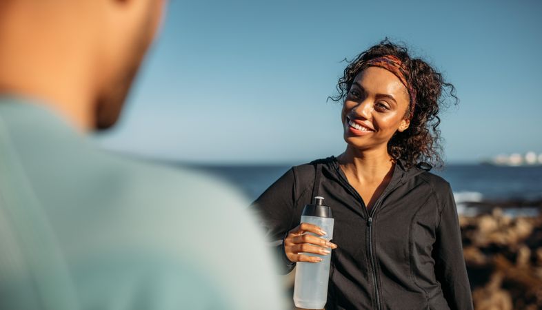 Smiling woman relaxing after a workout drinking water