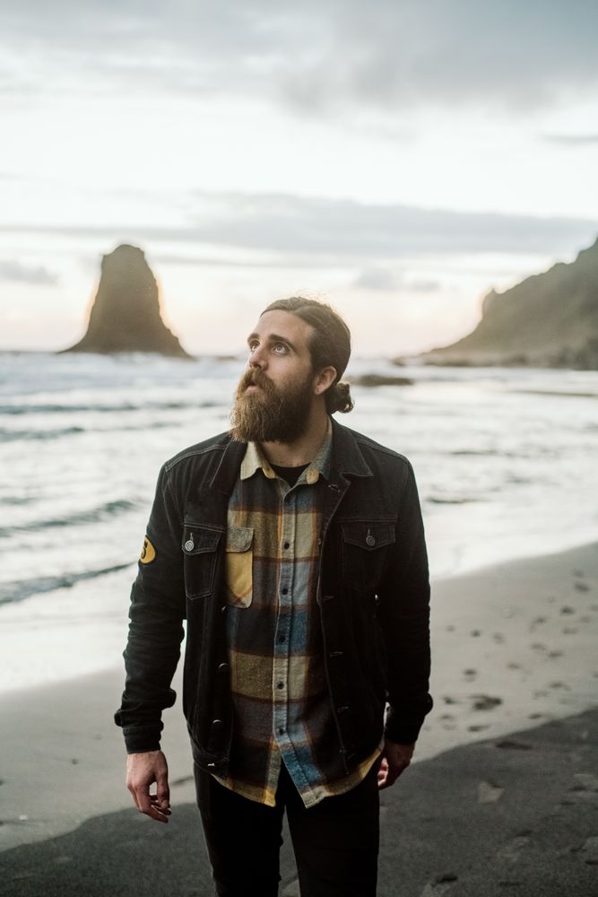 Bearded traveler looking up near sea