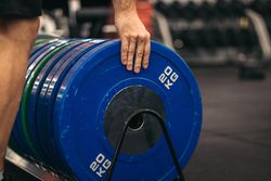 man taking a weight plate in a gym