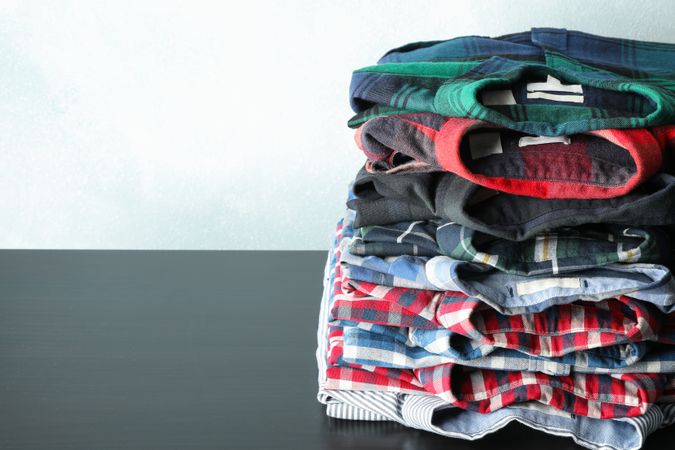 Stack of different shirts on table, space for text
