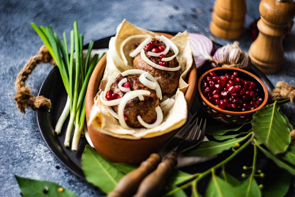 Traditional Georgian meal of abkhazura meat cutlets on plate with spring onions
