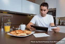 Man sitting at breakfast with credit card and tablet 0Lgxrb