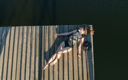 Young female lying down on pier on nature