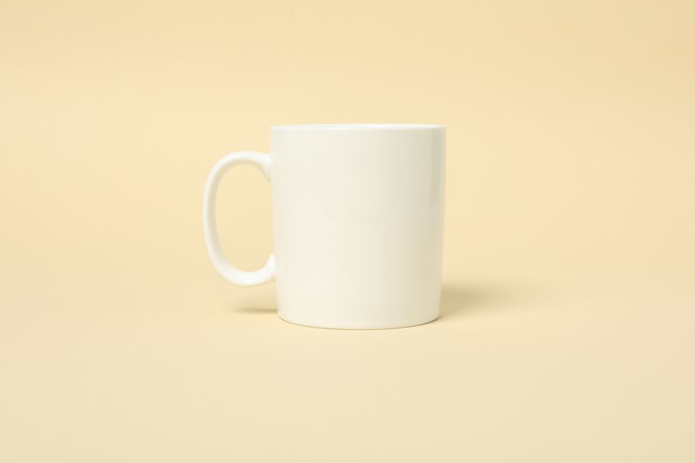 Empty cup on beige background, space for text