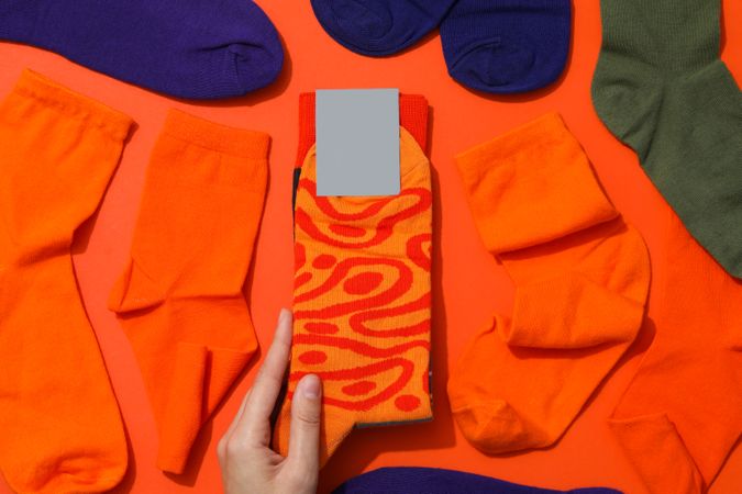 Female hand and socks on orange background