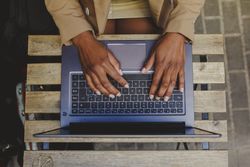 Black woman sitting at table and browsing on laptop in cafe