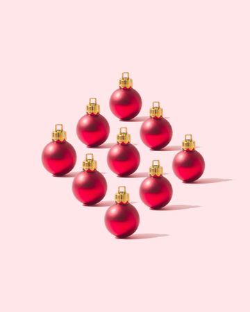 Nine red round ornaments on pink background
