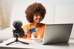 young latina woman with afro hair happy to shop online with laptop and pay by credit card