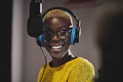 Smiling Black female in headphones near microphone