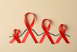 Awareness red ribbons on beige background, copy space