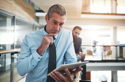 Man in business attire focused on his work using a  tablet