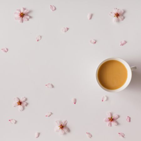 Aerial view of coffee or tea with flowers and petals on light background