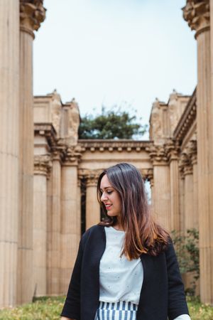 Active woman walking between ancient columns of building outside